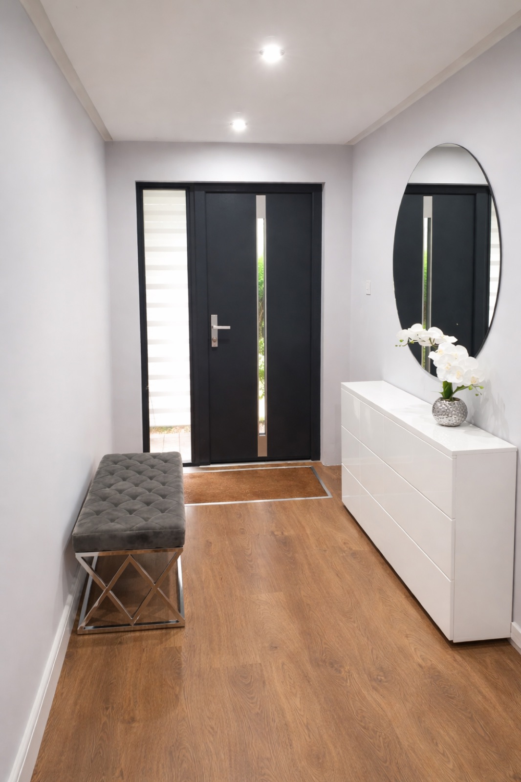 A light filled hallway leading to a black front door